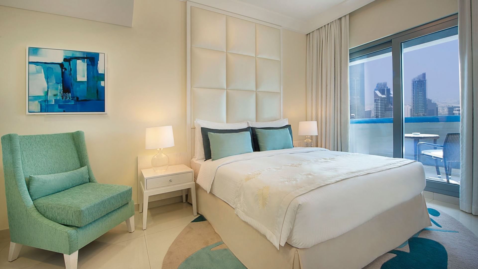 Cozy bed with side tables, chairs and balcony area in Three Bedroom Suite at DAMAC Maison Dubai Mall Street