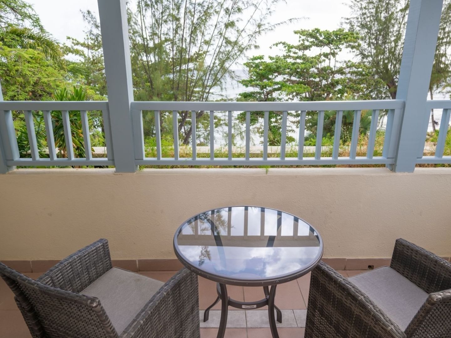 Two wicker chairs and a glass table on a balcony at Savannah Beach Hotel.