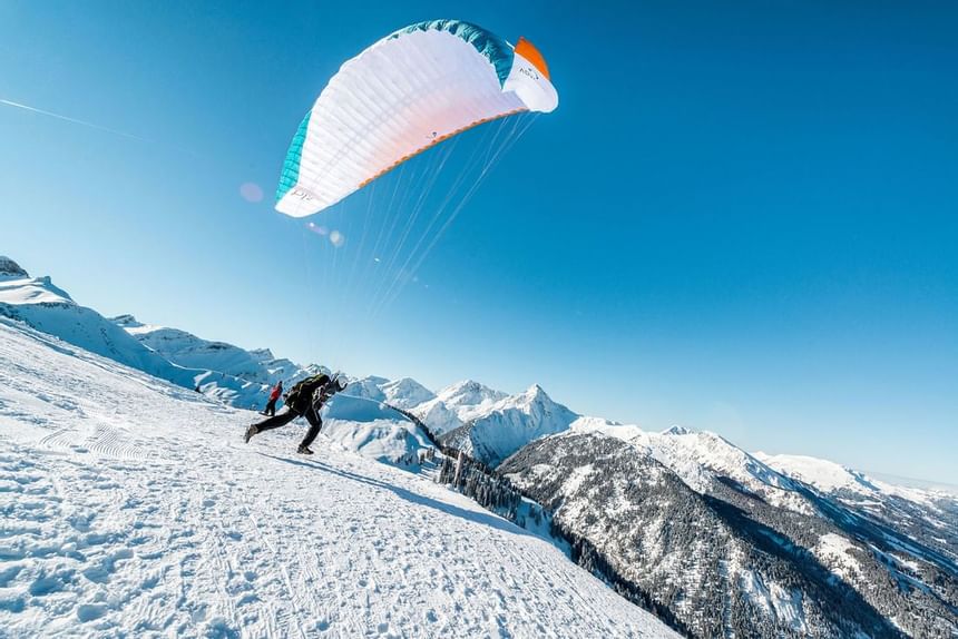 Man paragliding in Tannheimer Valley near Liebes Rot in winter