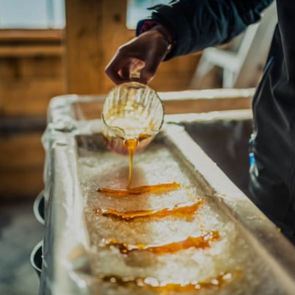 Person pouring maple syrup into a container with ice.