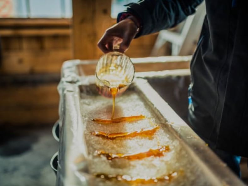 Person pouring maple syrup into a container with ice.