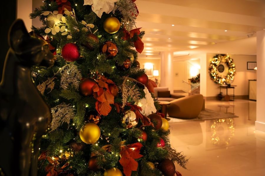Elegantly decorated Christmas tree with red and gold ornaments in the festive lobby of The May Fair Hotel