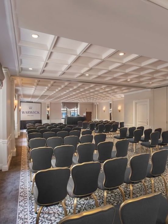 Theater set-up facing screen under warm light in Surrey meeting room at Warwick New York