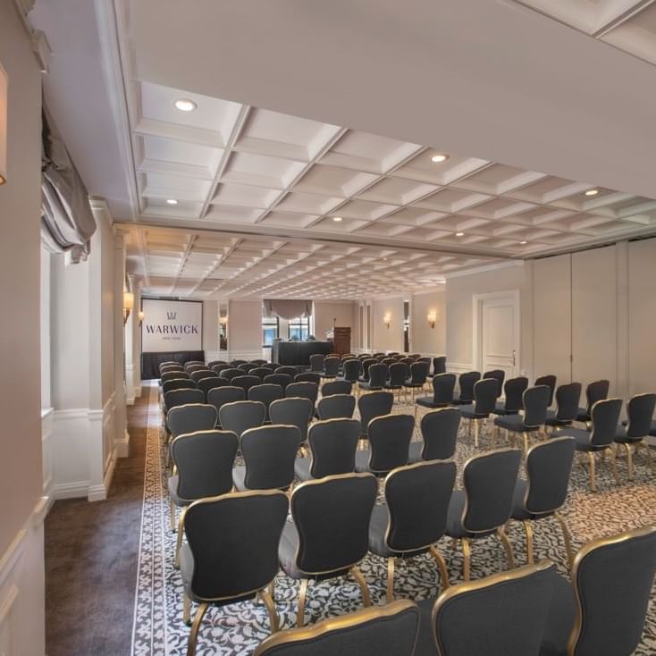 Theater set-up facing screen under warm light in Surrey meeting room at Warwick New York