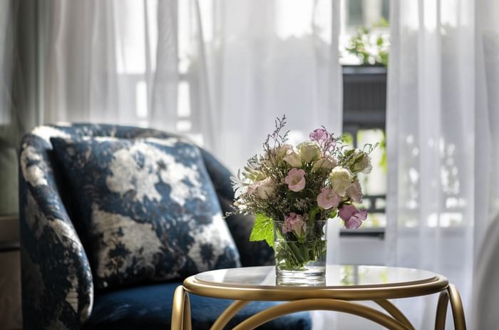 Bouquet de fleurs fraîches sur une table basse dorée près d'un fauteuil bleu à l'Hotel Westminster Warwick Paris