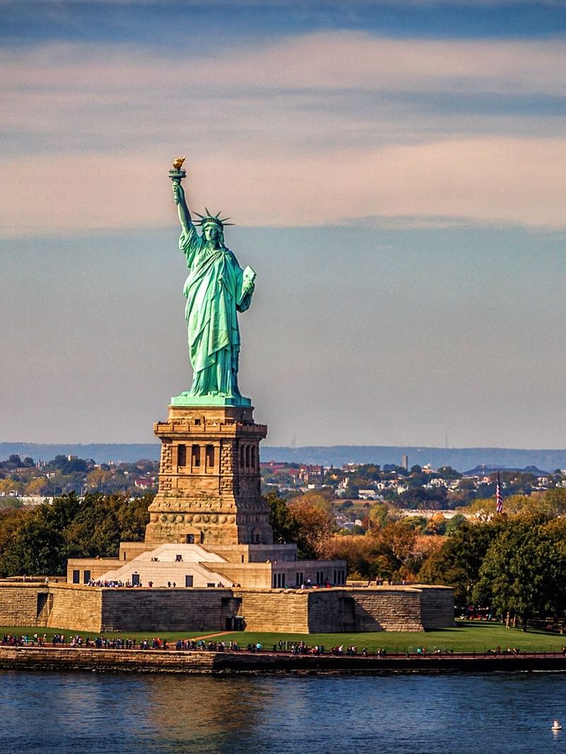 Statue of Liberty in Upper New York Bay surrounded by water and trees.