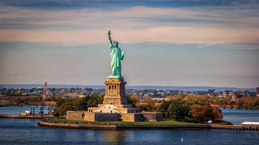Statue of Liberty in Upper New York Bay surrounded by water and trees.