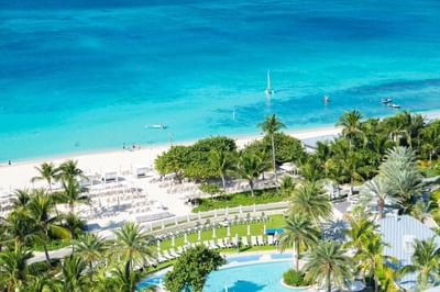 Aerial view of the Residences at Seafire's sandy beach, and pools surrounded by lush palm trees