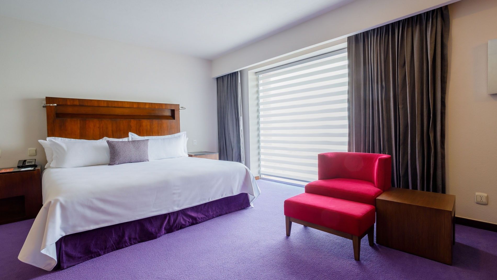 Spacious King Junior Suite featuring a plush purple carpet and a red accent chair at Camino Real Pedregal Mexico