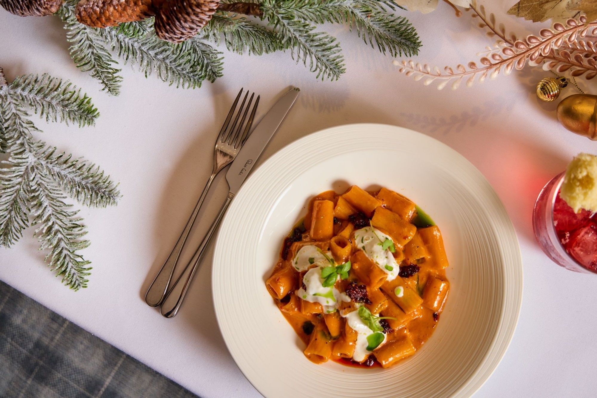 Pasta dish with cream and herbs on festive table with pine branches and ornaments part of the Festive Set Menu at Whitcomb's.