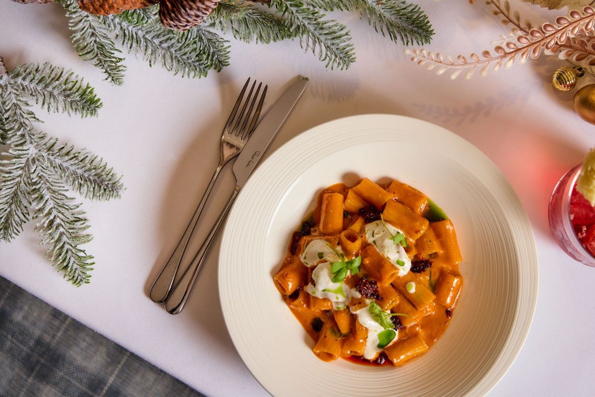Nudelgericht mit Sahne und Kräutern auf einem festlich gedeckten Tisch mit Tannenzweigen und Weihnachtsschmuck – Teil des festlichen Menüs bei Whitcomb's.