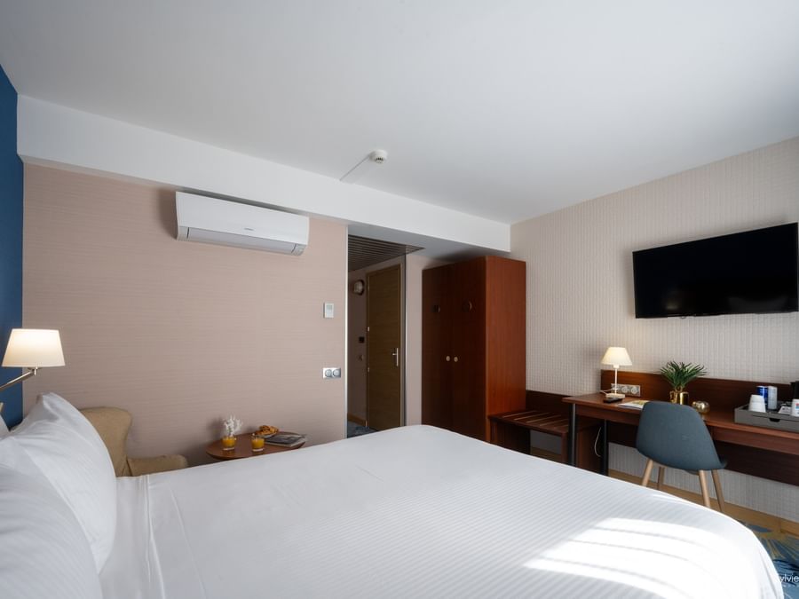 Chambre élégante avec lit, bureau et télévision au mur chez Hôtel Le Yachtman.