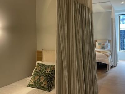 A cozy bedroom with beds, curtains, and a lamp within a 4 Bedroom Twin Share Apartment at UniLodge Brisbane City.