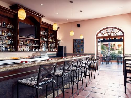 Bar La Suerte with a selection of bottles and bar stools at Hacienda del Mar Los Cabos