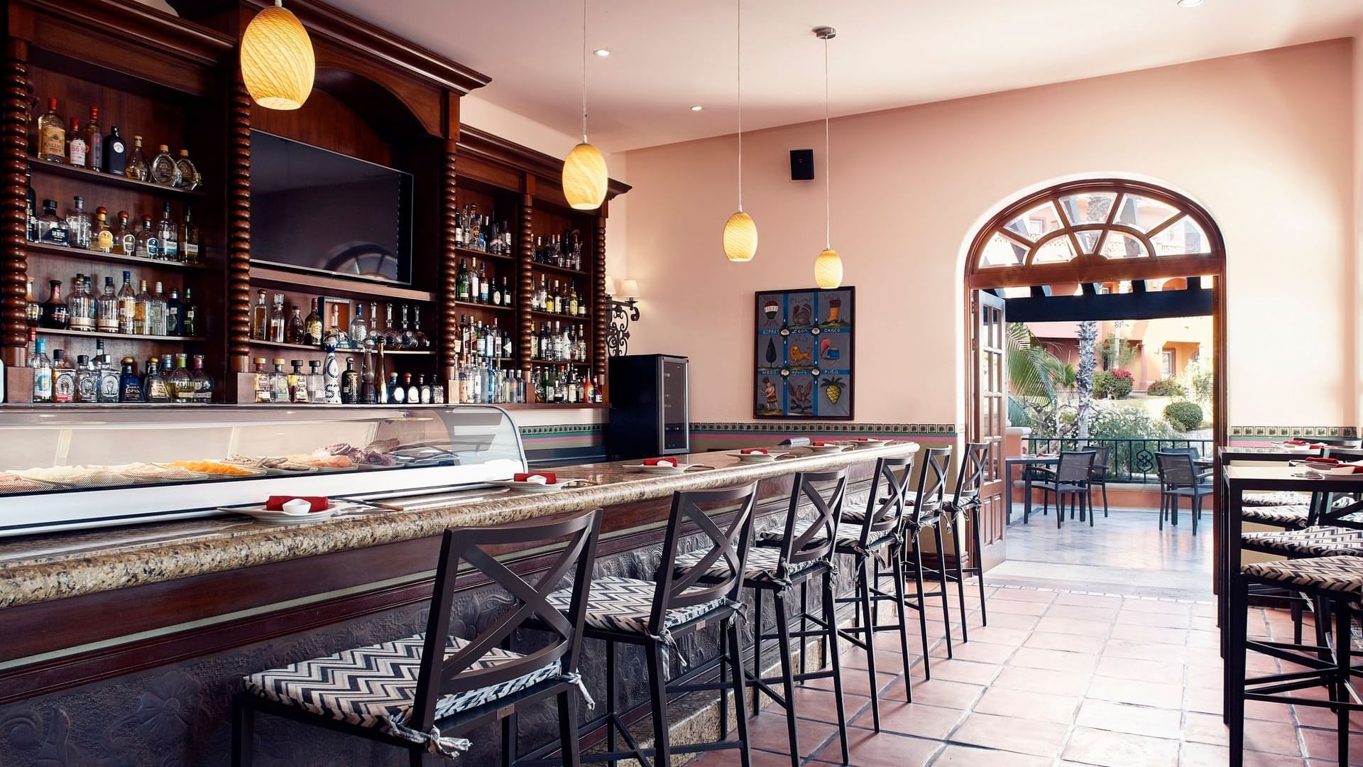 Bar La Suerte with a selection of bottles and bar stools at Hacienda del Mar Los Cabos