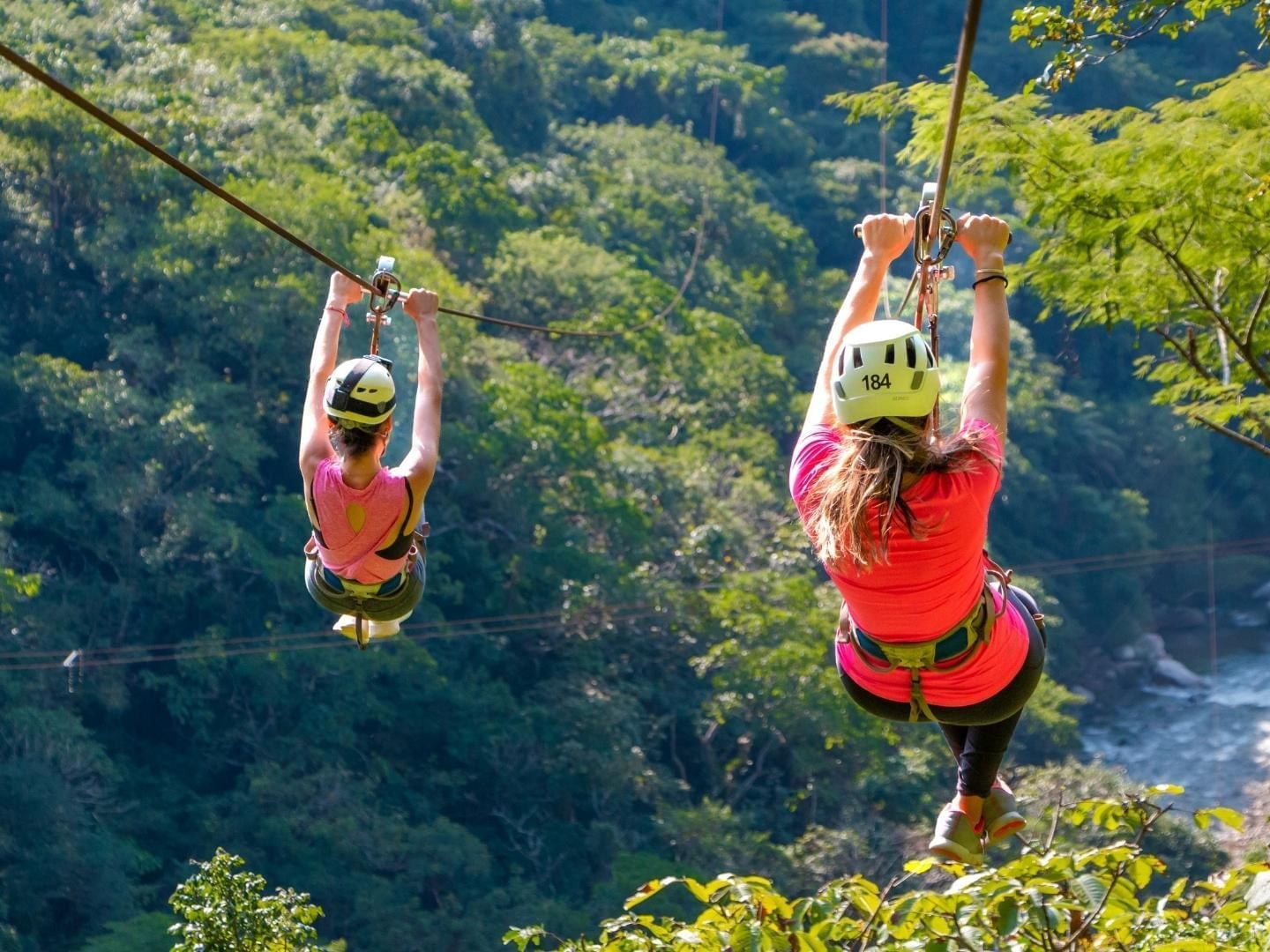 Two people ziplining through Canopy River near Plaza Pelicanos Grand Beach Resort
