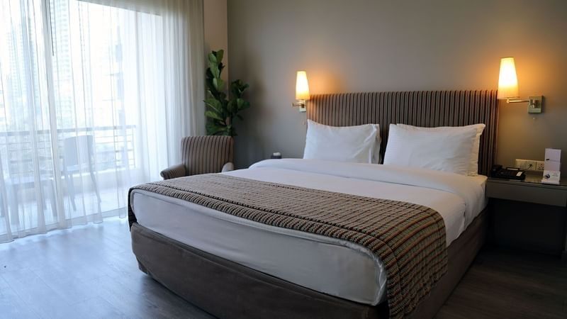 Bed with side tables and a couch by the window in Premium Room at Warwick Palm Beach Hotel