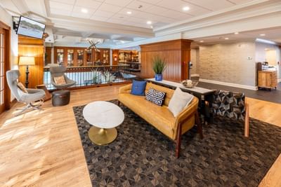Upper TV lounge area with a yellow sofa and marble coffee table at The Boulevard Inn & Bistro