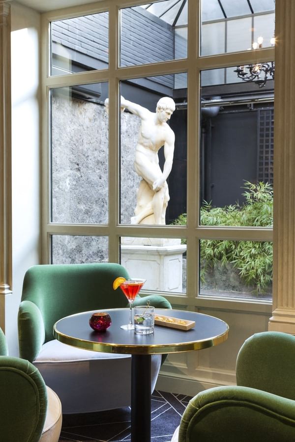 Cocktails on a bistro table overlooking a courtyard statue at Hotel Barsey by Warwick