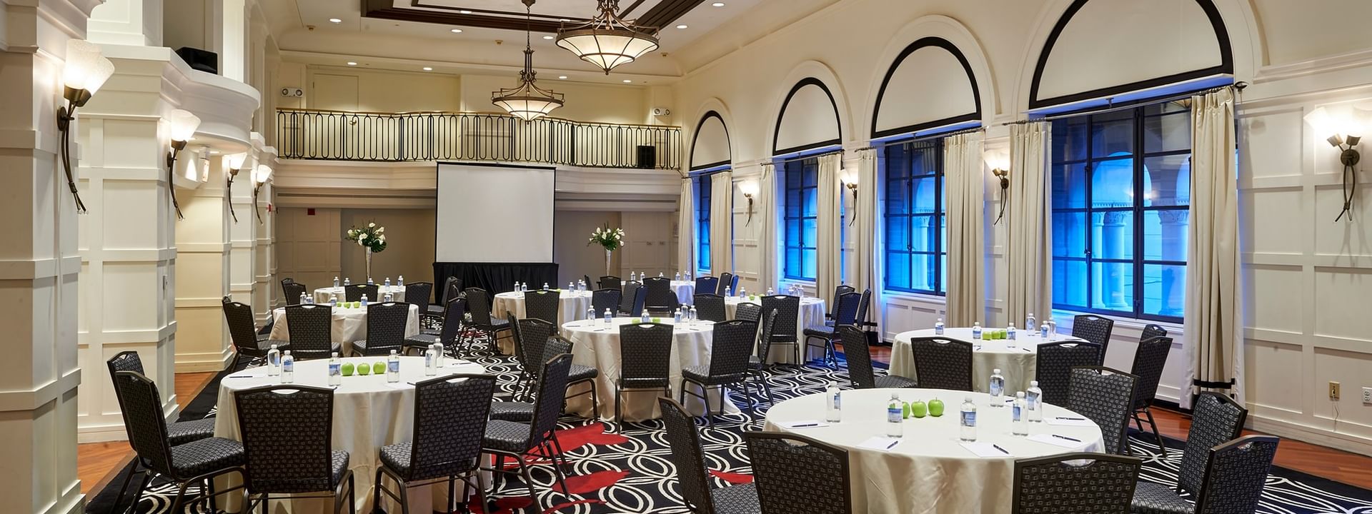 Set up banquet tables facing a projector screen near window in Buckingham Ballroom at Warwick Allerton Chicago