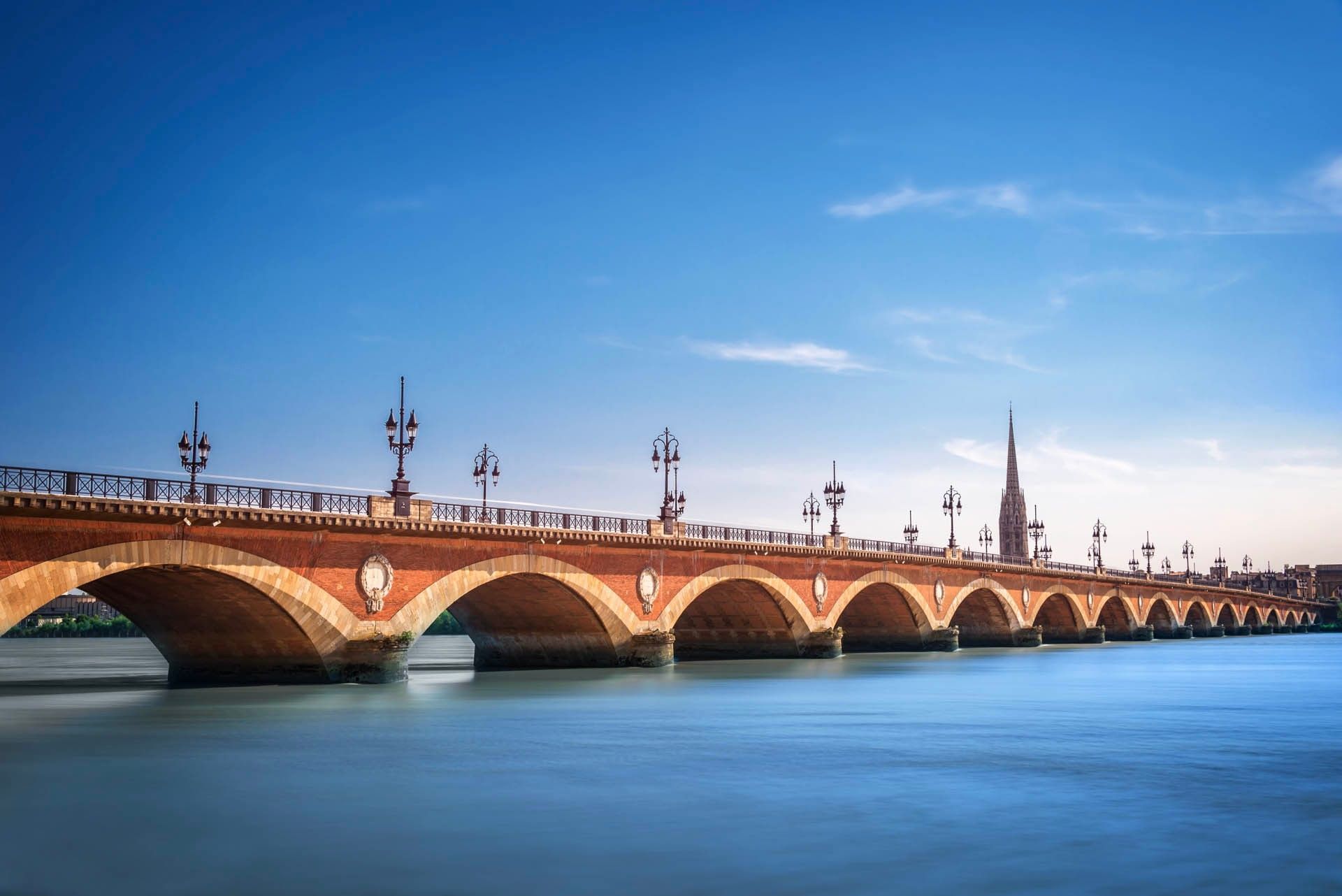 View of the stone arched Pont de Pierre bridge across the wide Garonne River near ResidHotel Bordeaux Galerie Tatry