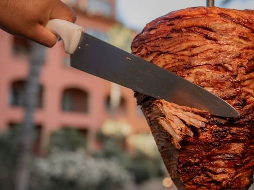 Knife carving grilled meat for tacos al pastor at Tahona restaurant at Hacienda del Mar Los Cabos.