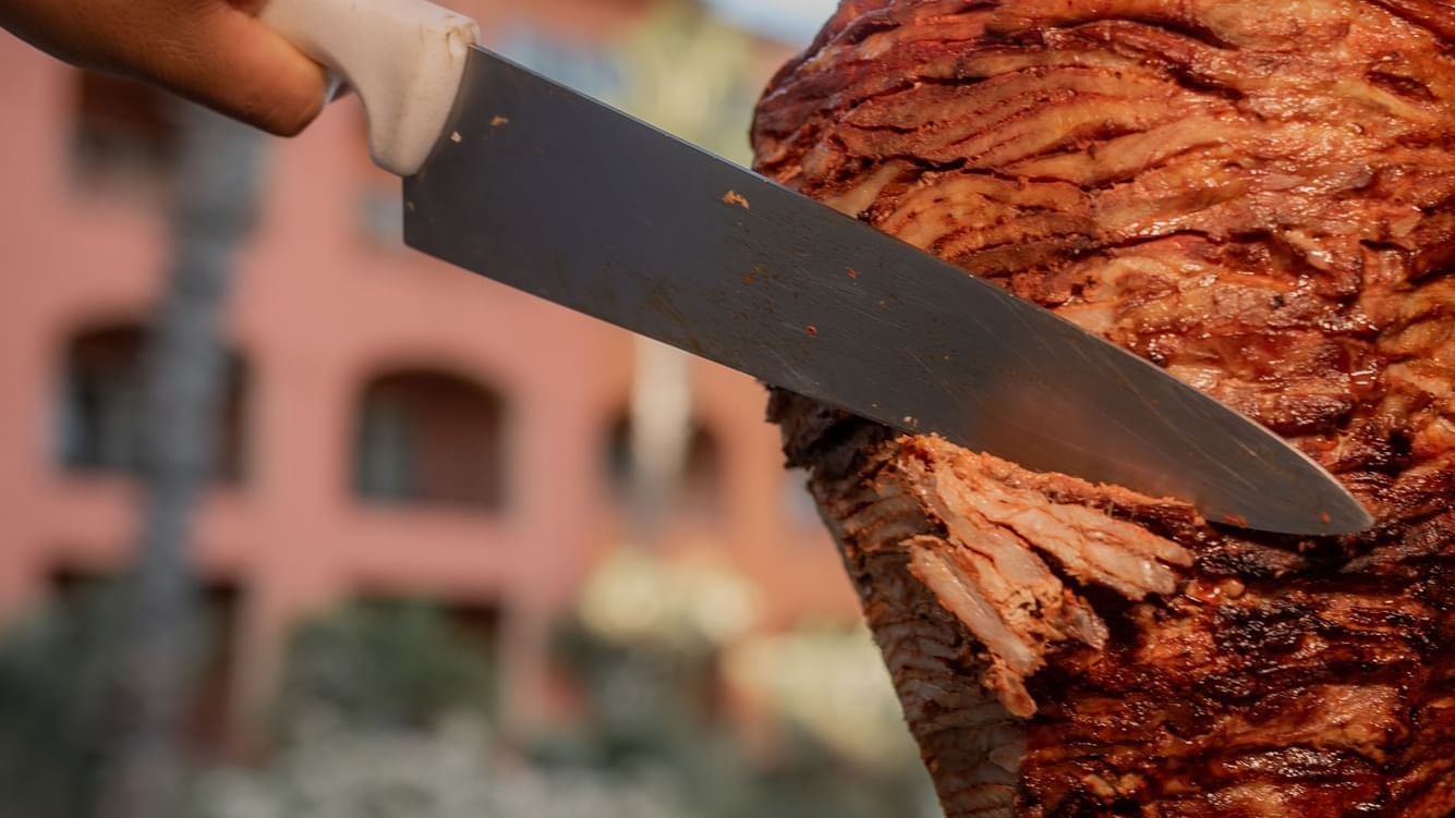 Knife carving grilled meat for tacos al pastor at Tahona restaurant at Hacienda del Mar Los Cabos.