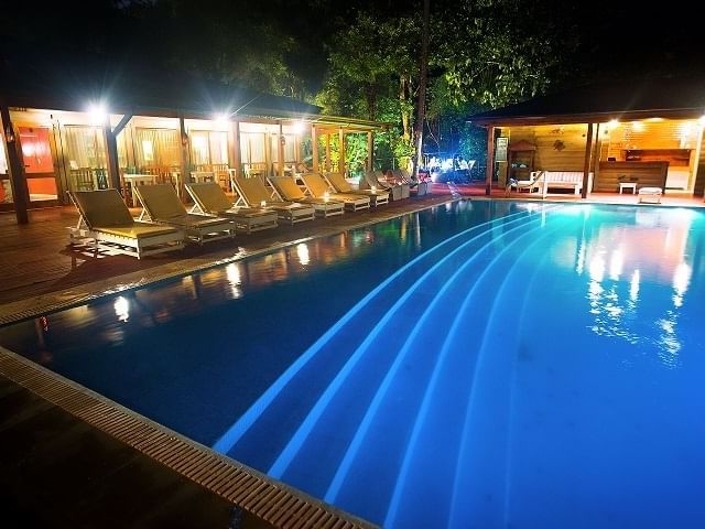 View of Sunbeds by the outdoor pool at night near DOT Hotels
