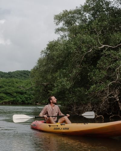 Hombre remando en un kayak amarillo por las tranquilas aguas de los manglares cerca de Morgan's Rock Reserve & Ecolodge.