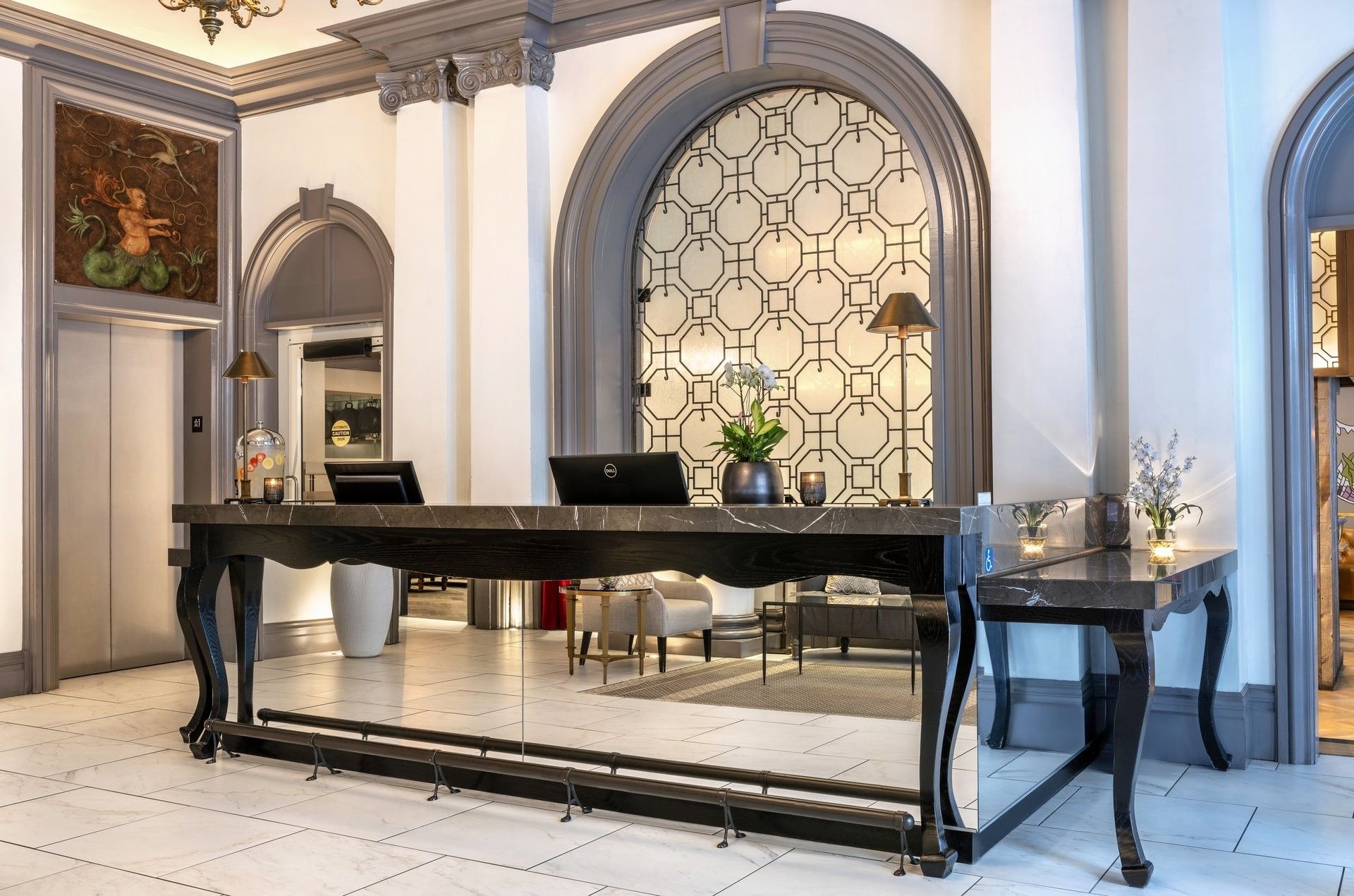 Marble reception desk by an arched window under ornate pillars in the lobby at Warwick San Francisco
