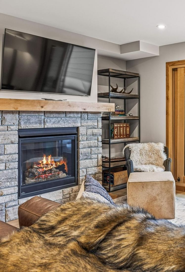 Cozy living room with fireplace, mounted TV and shelving unit at Spring Creek Vacations