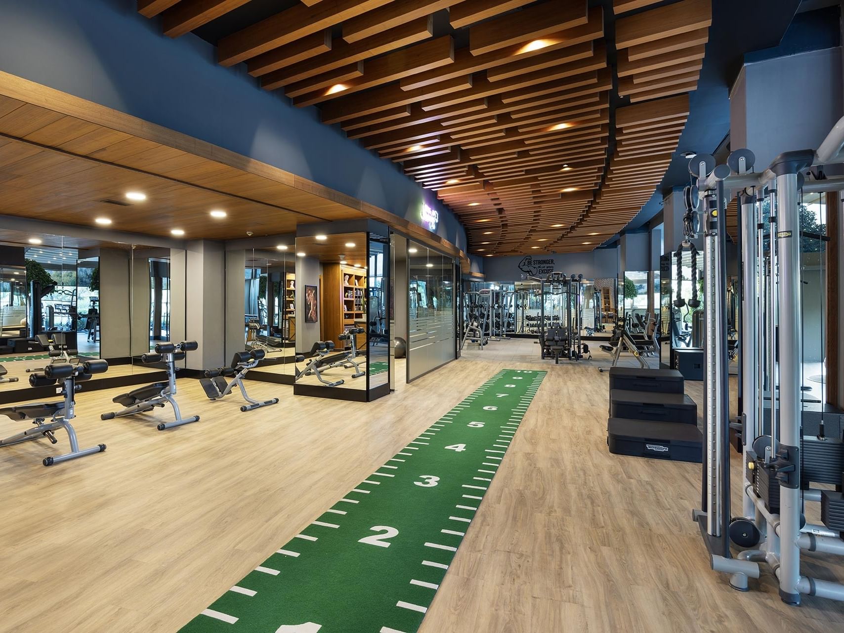 A spacious, modern gym with fitness equipment and green-striped mats at Titanic Luxury Collection Bodrum.