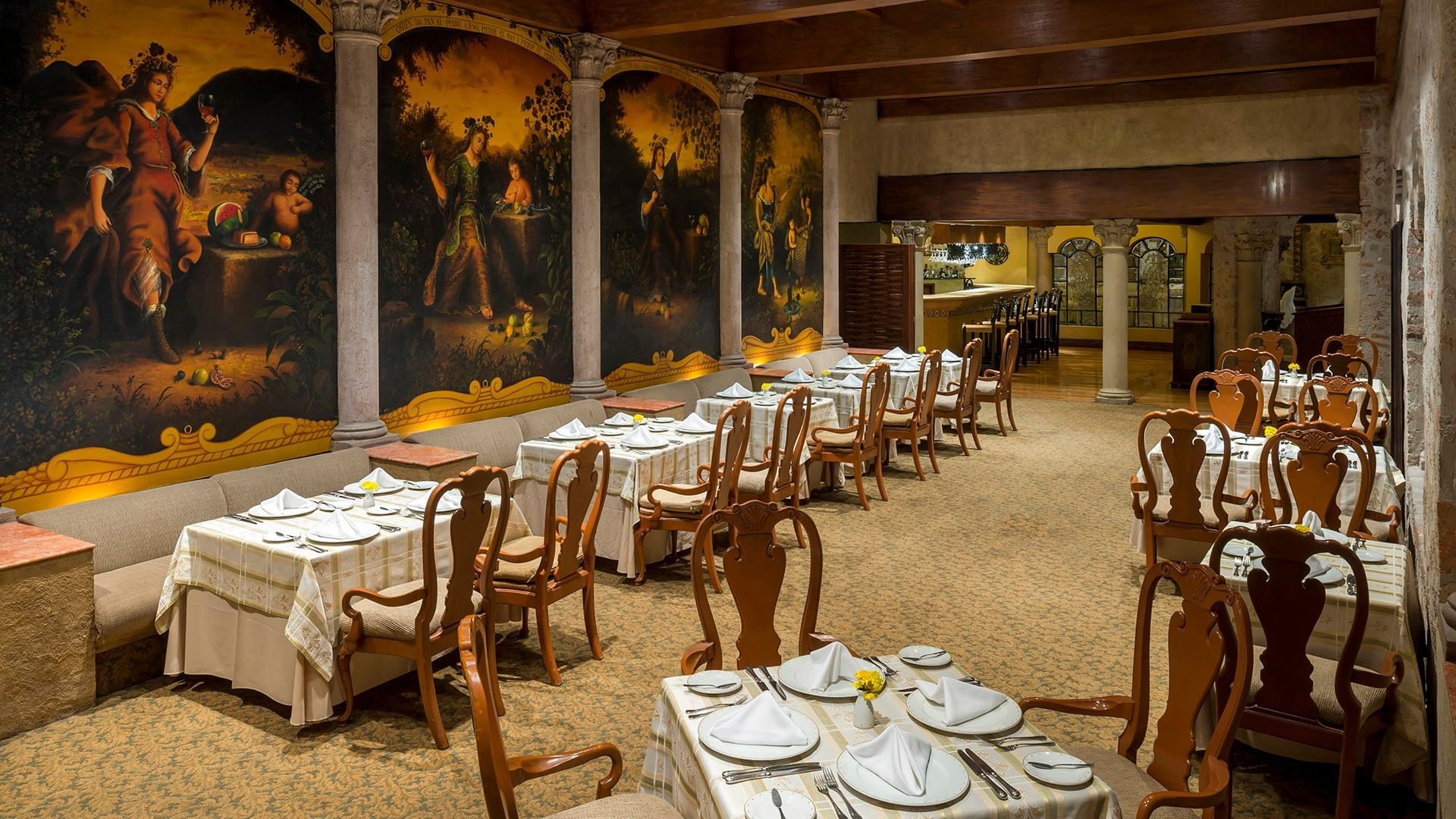 Elegant dining room with colonial-style murals, wooden chairs, and white-clothed tables at Quinta Real Aguascalientes