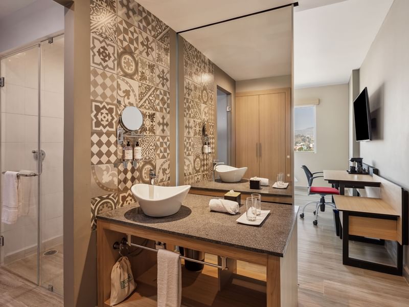 Modern sink area and a glass door to a bathroom in Standard King at Gamma Hotels