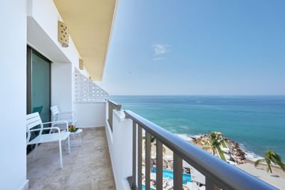 Private balcony with a table and chairs offering stunning ocean and beach views.