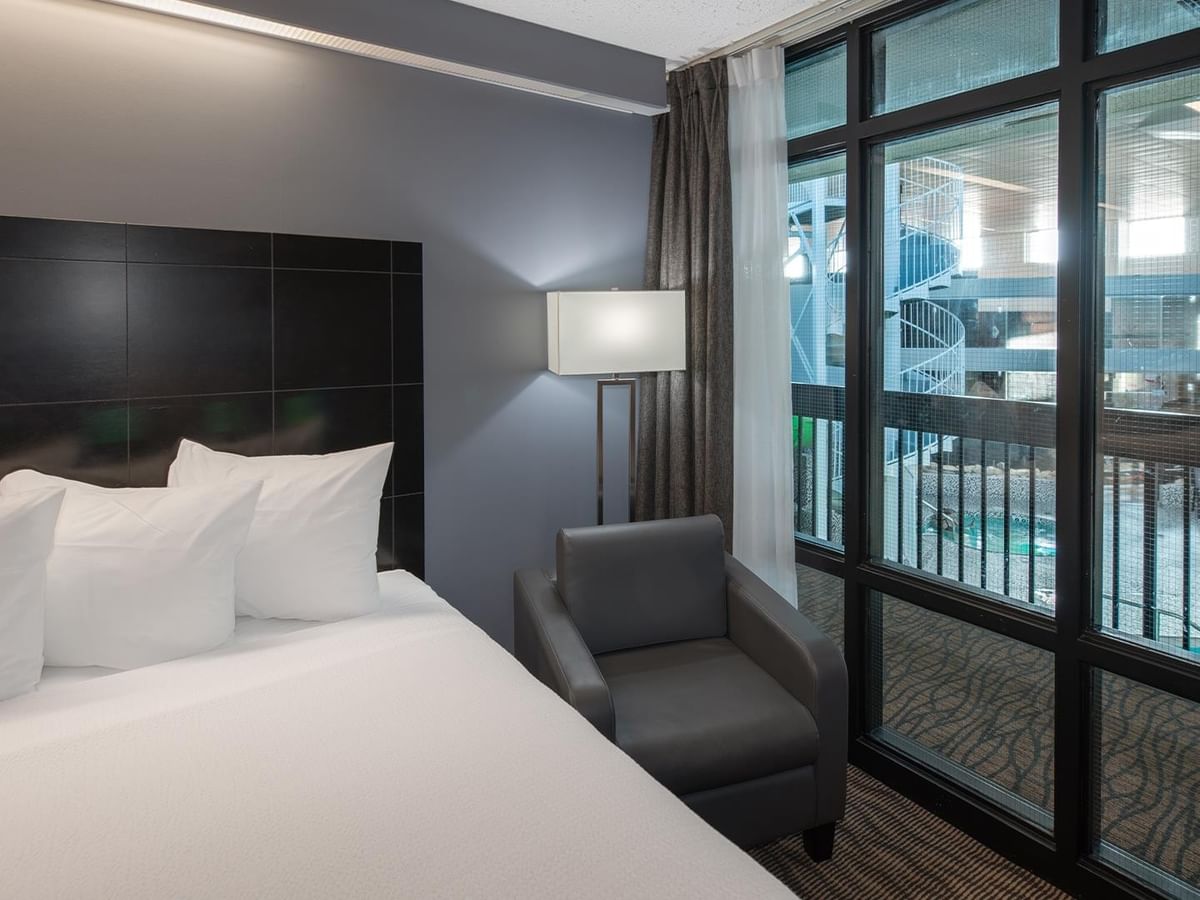 A hotel room with two queen beds, large windows, and a chair.