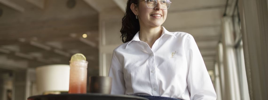 Waitress holding trays with meals & drinks at Hoteles Australis
