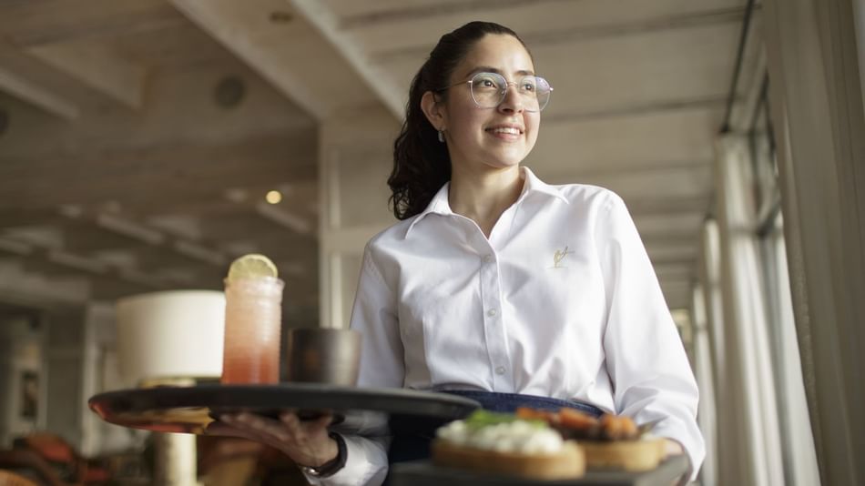 Waitress holding trays with meals & drinks at Hoteles Australis