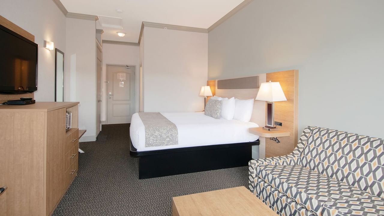 Hotel room with king bed, TV, mirror, sofa bed, and coffee table