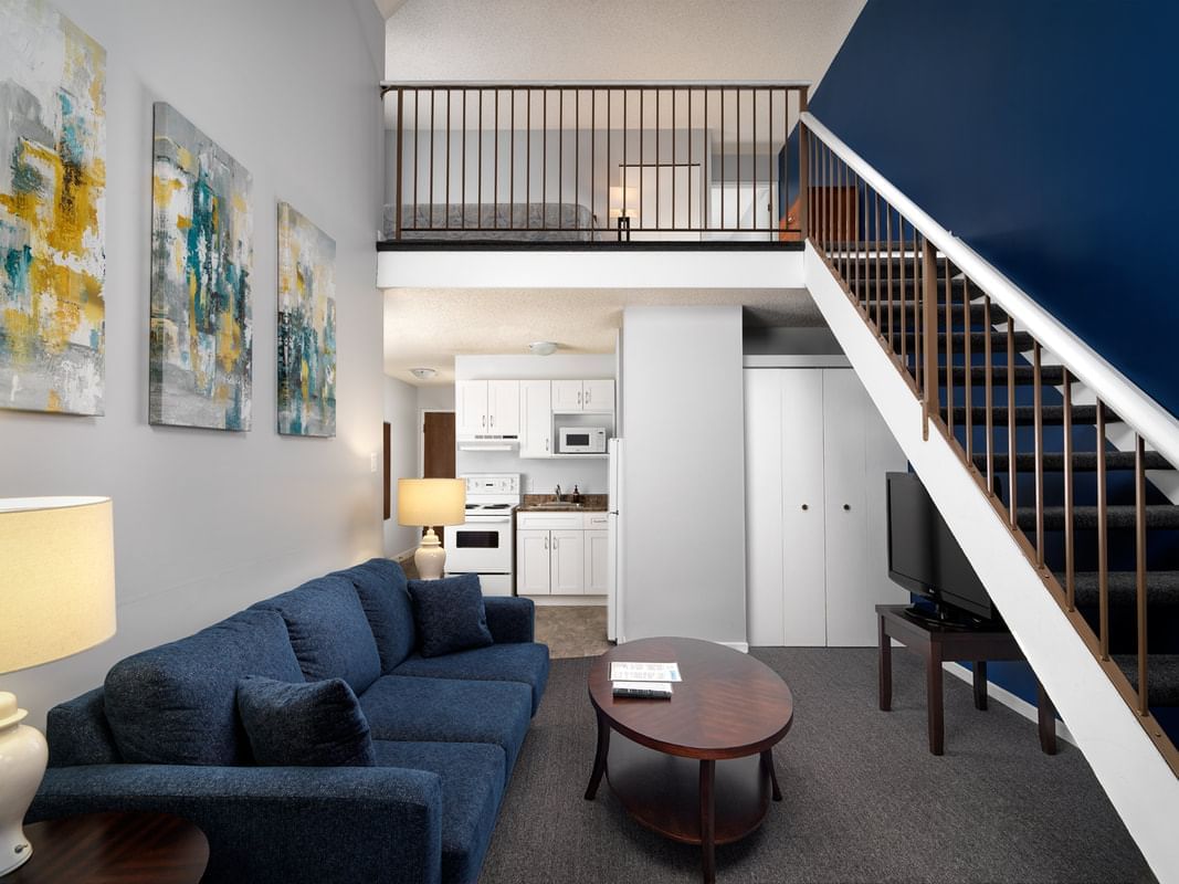 Interior of living room featuring a staircase & blue couch in Manchester Suite at Huntingdon Manor