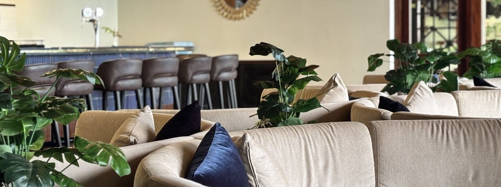 Curved sofas with blue cushions by green plants under bamboo lights in Hibiscus Lounge at Warwick Fiji Resort and Spa