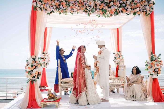 Beach wedding ceremony with a couple under a floral arch at Diplomat Beach Resort