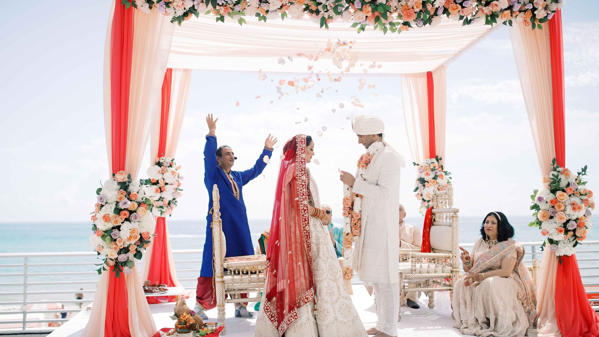 Beach wedding ceremony with a couple under a floral arch at Diplomat Beach Resort