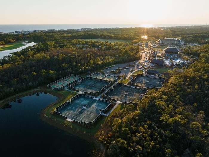 Sunset aerial view of Camp Creek Inn's tennis and pickleball courts, pools, and golf course