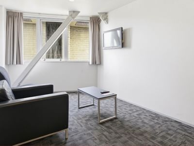 Small room with couch, coffee table, and wall-mounted TV at Student Living Auckland Anzac.