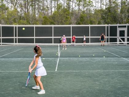 Players enjoying tennis and pickleball on outdoor courts surrounded by trees at Camp Creek Inn in Inlet Beach