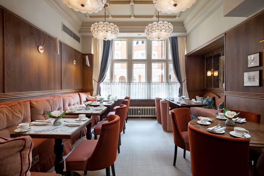 Dining area with tables set by orange seating under globe lights at The Capital Hotel, Apartments and Townhouse
