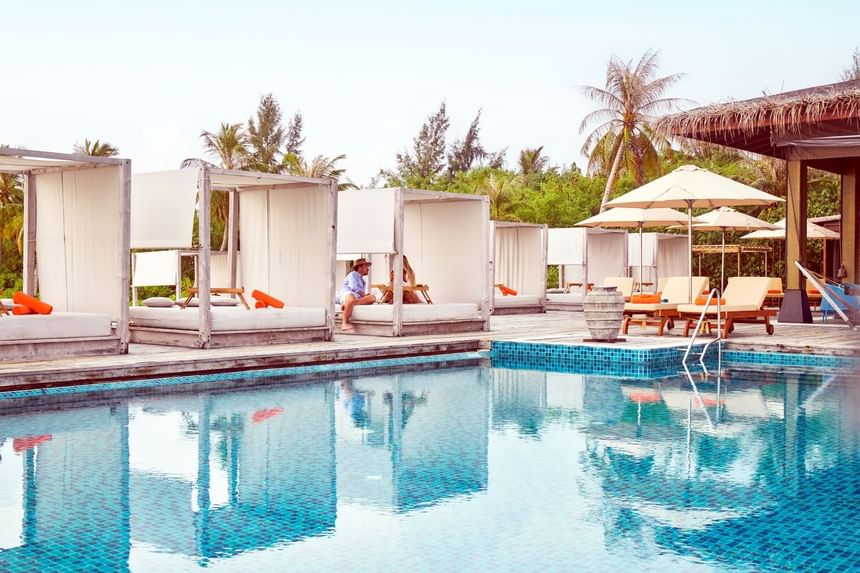 Grand Park Kodhipparu pool with cabanas, loungers, and a couple relaxing by the water