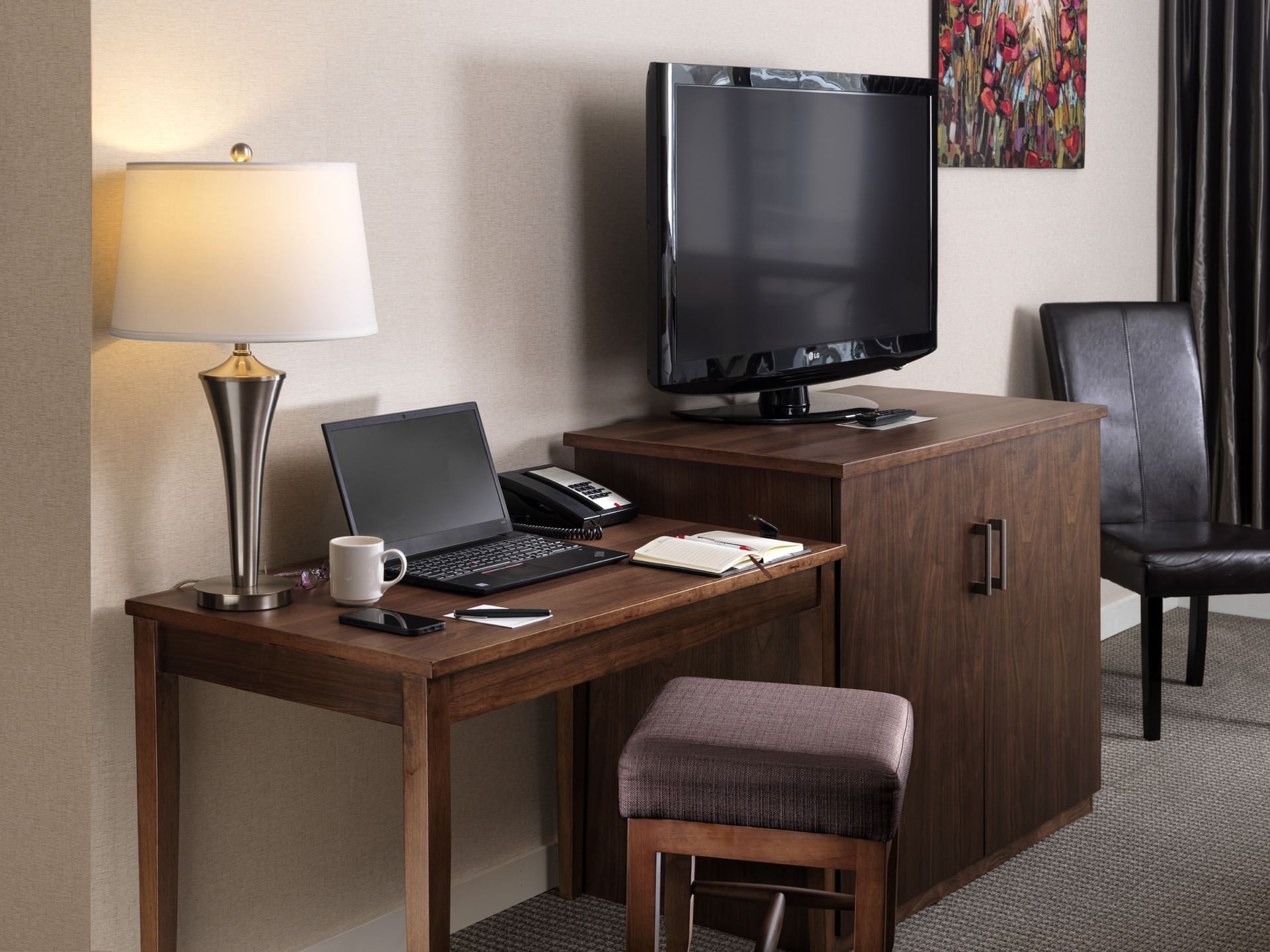 TV stand by a desk with items in a Room at Huntingdon Manor