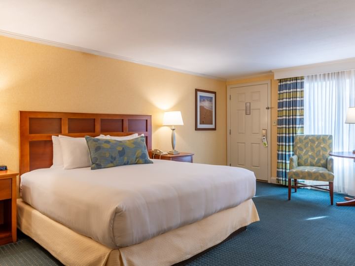 A hotel room with a large bed, chair, and window